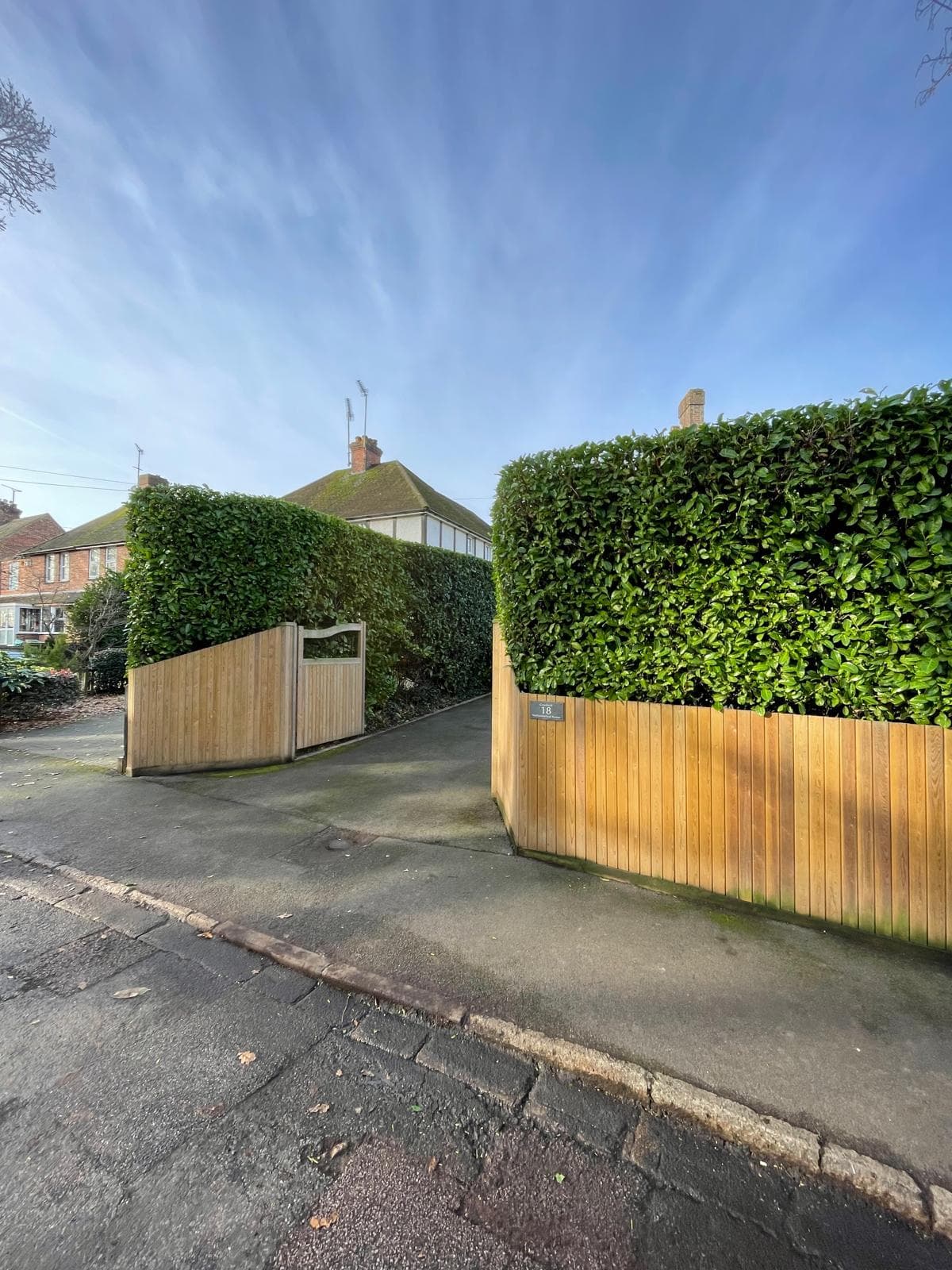 Trimmed hedge framing driveway entrance with gate